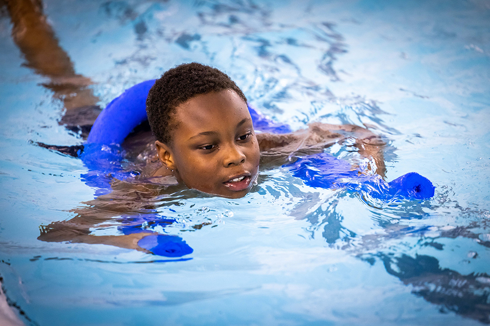 Boy learning to swim with swimming aid