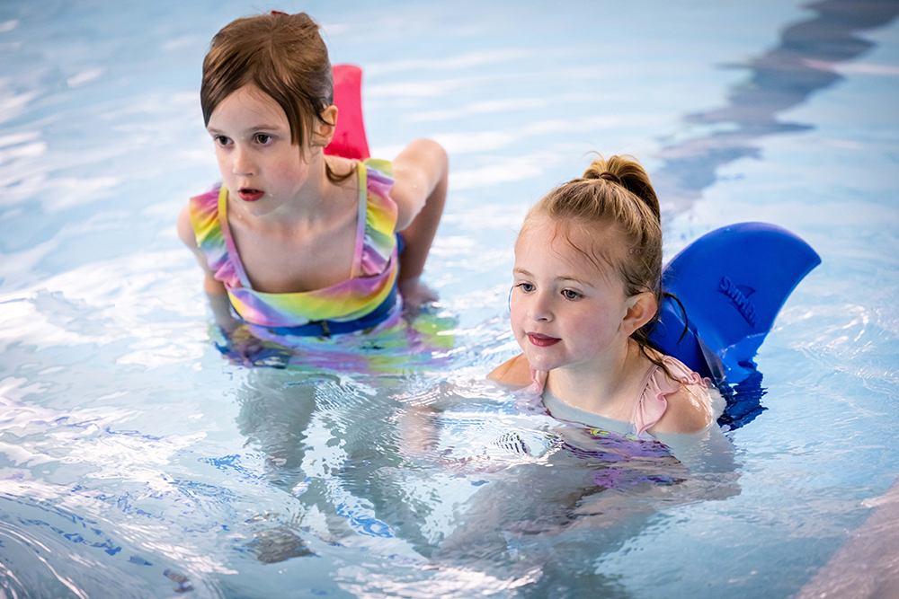 Two girls learning to swim with swimming aids