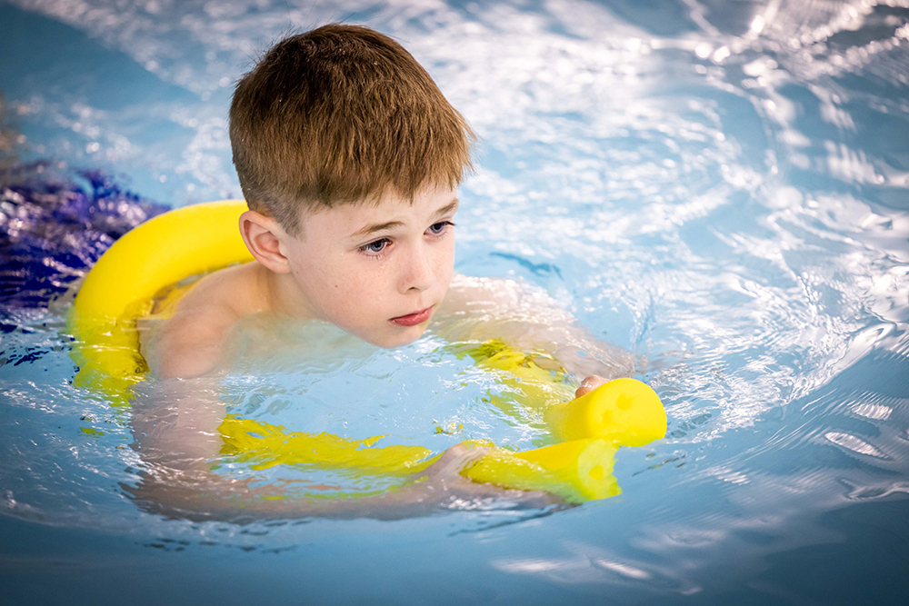 Boy with swimming aid floating in the pool
