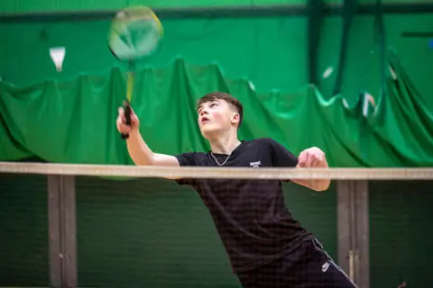 Young person playing badminton in the sports hall at Castle Leisure Centre