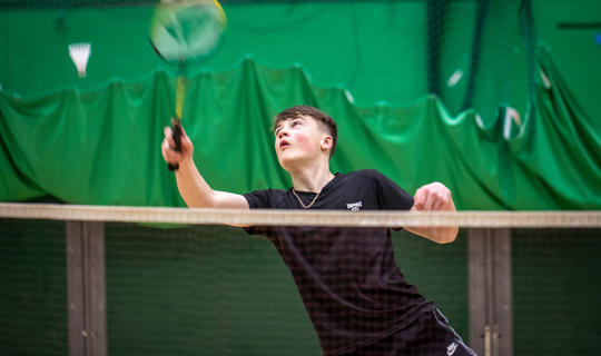 Young person playing badminton in the sports hall at Castle Leisure Centre