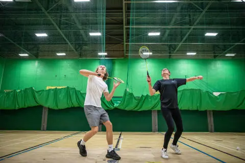 Man and woman playing badminton in the sports hall at Castle Leisure Centre