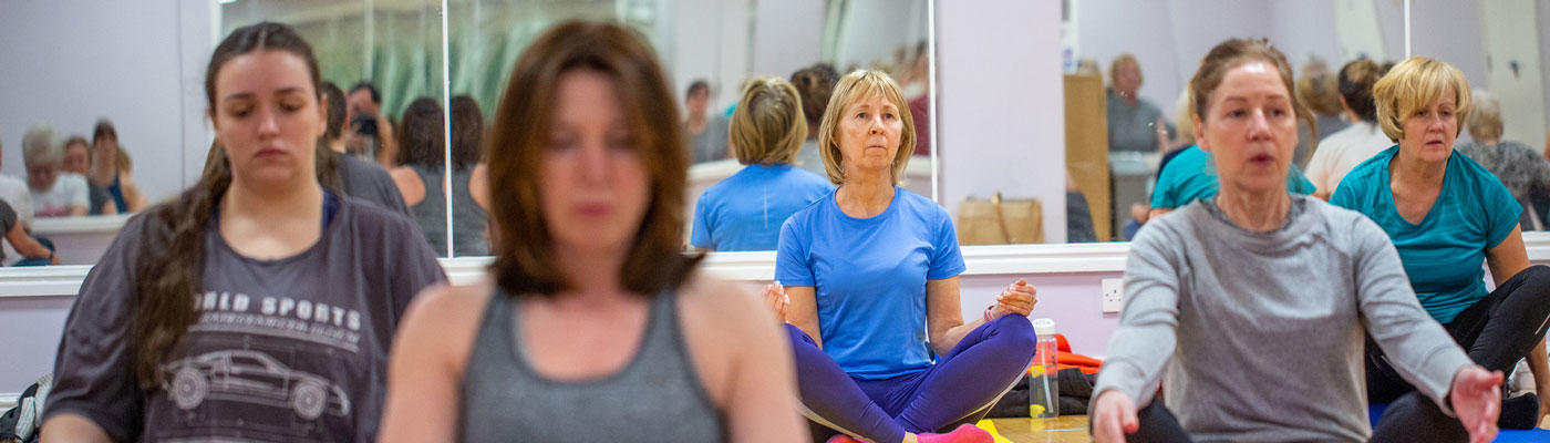 Five women sat crossed-legged in a fitness studio