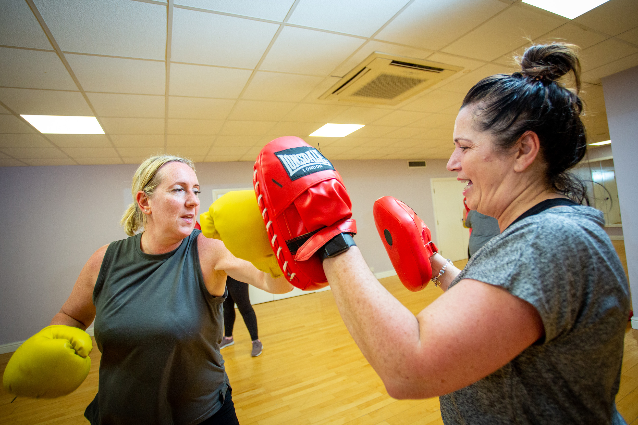 Woman wearing boxing gloves hitting the hand of another woman wearing boxing gloves