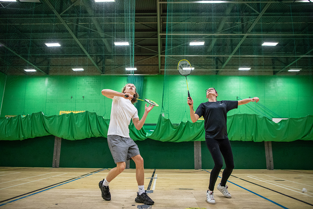 Mixed doubles game of badminton in the sports hall
