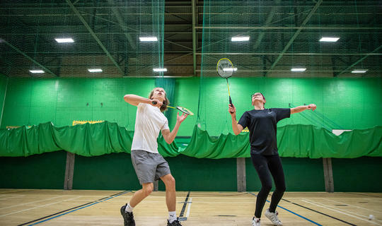 Mixed doubles game of badminton in the sports hall