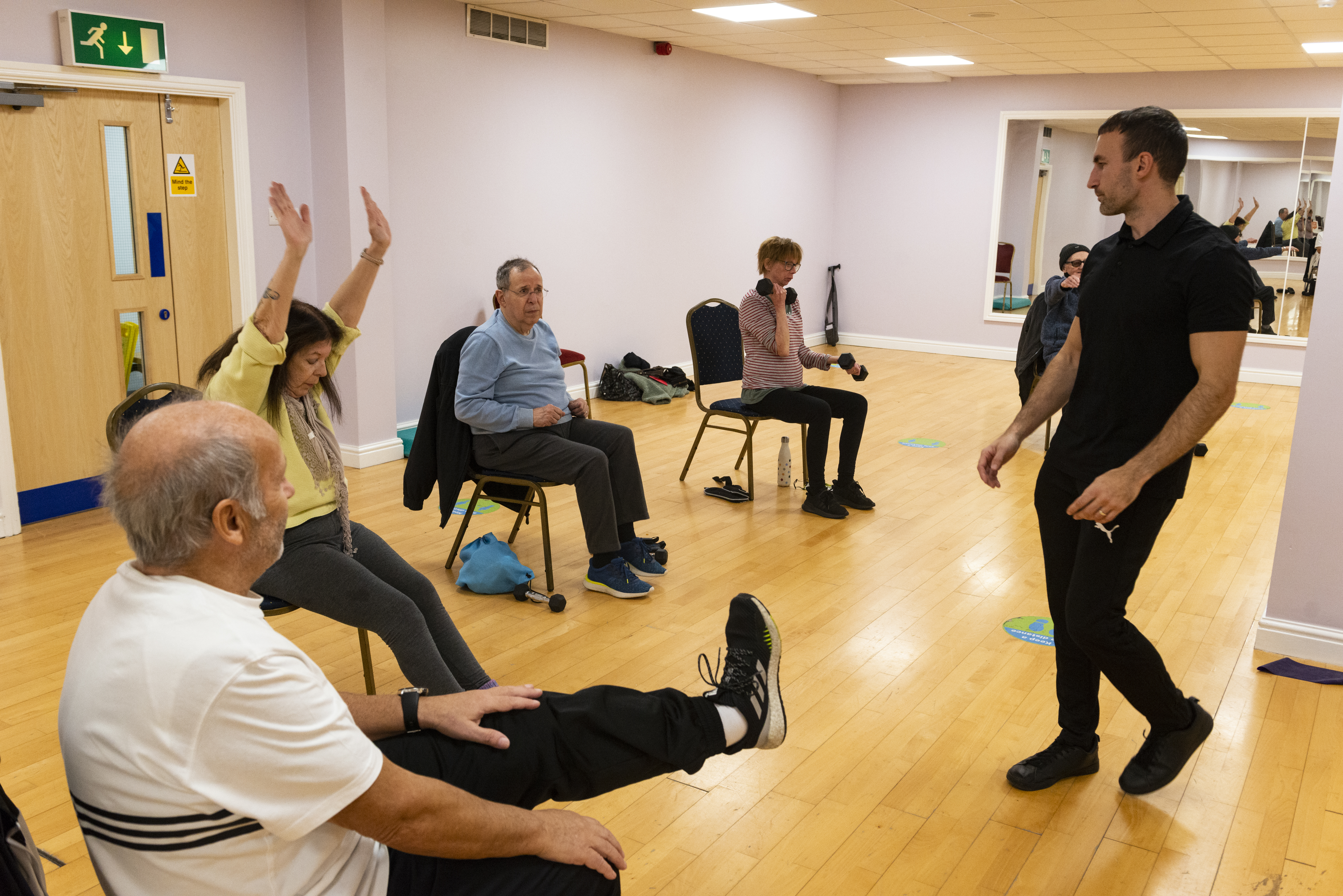 A group of people sat in chairs with a fitness instructor doing exercise