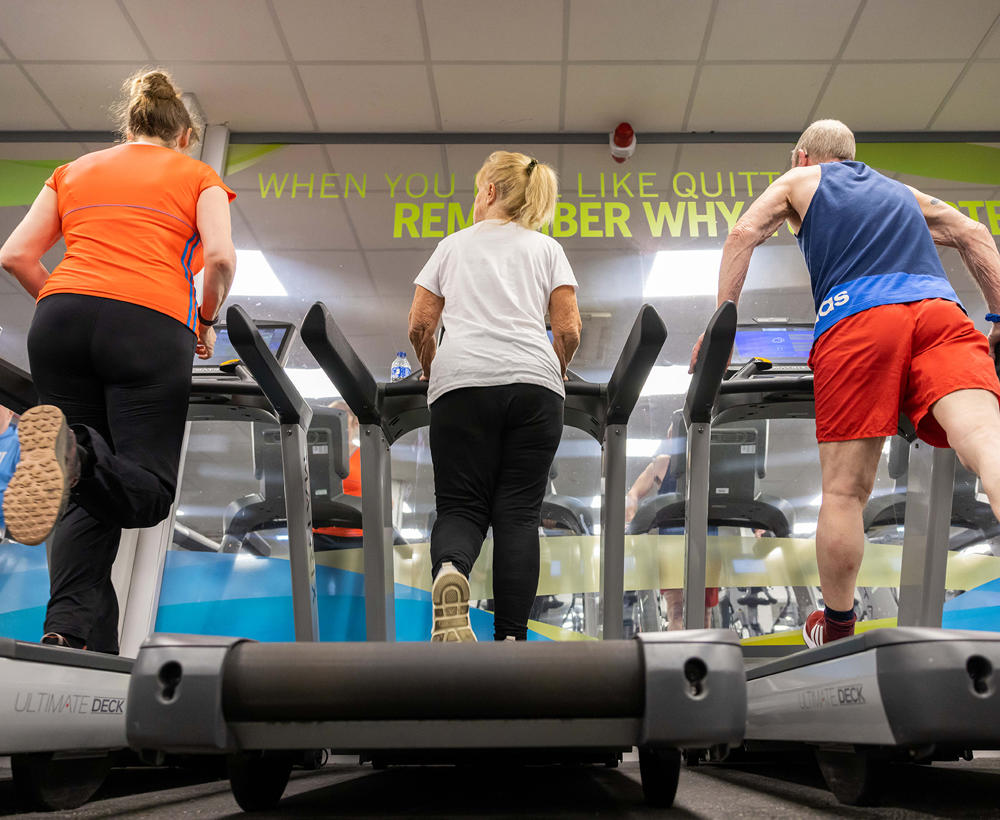 Two women and one man training on the running machines in the gym
