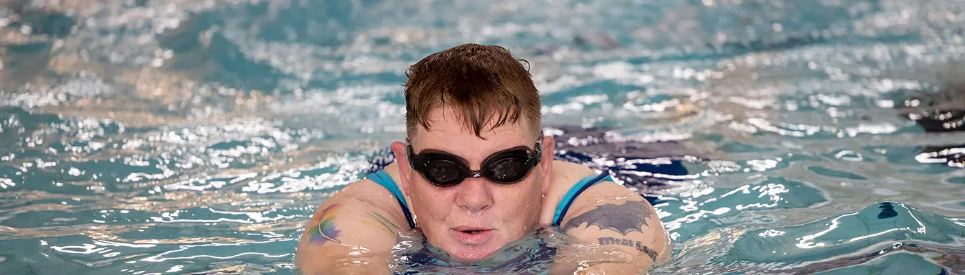 Man in a pool with a floatation aid learning to swim