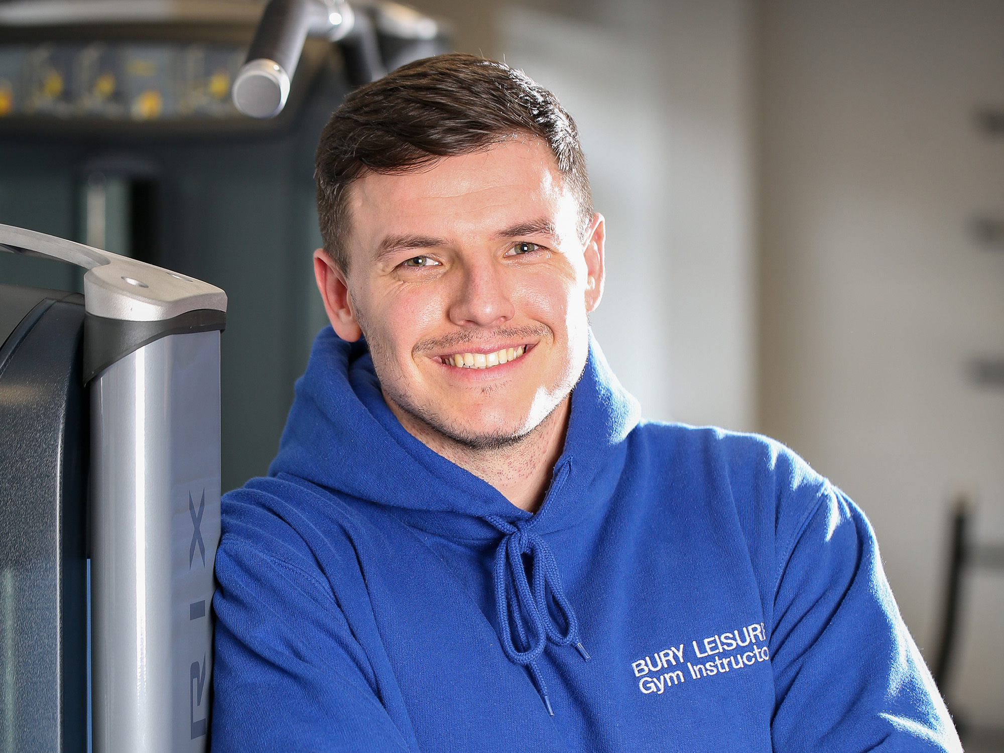 Male Bury Leisure gym instructor leaning against a piece of gym equipment