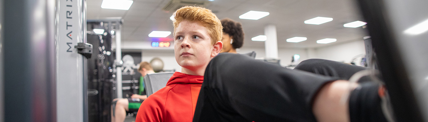 Young man using the strength equipment in a Bury Leisure gym
