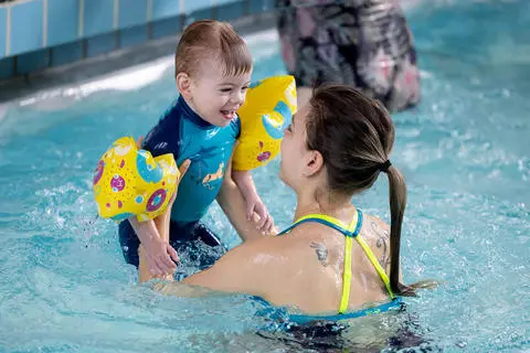 Boy being lifted out of the water at a parent and child swim session