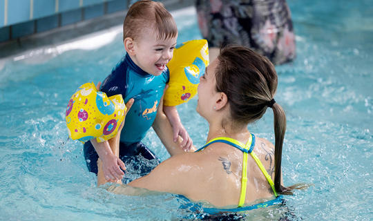 Boy being lifted out of the water at a parent and child swim session