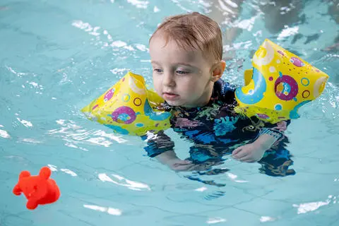 Child with arm bands floating in the pool