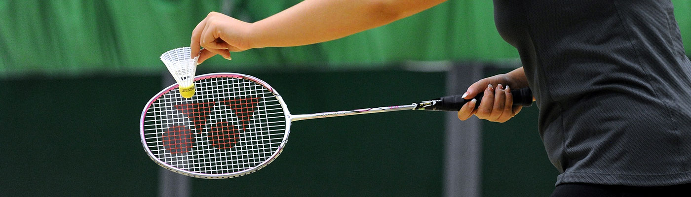 Hand holding badminton racquet and shuttlecock in the sports hall at Castle Leisure Centre