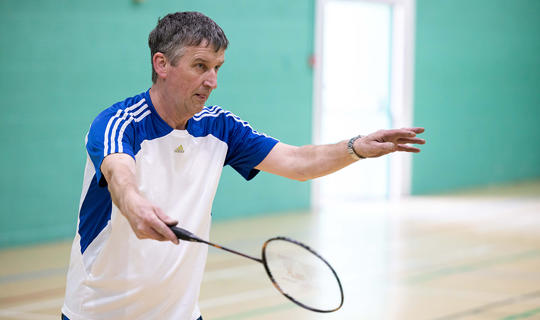 Man holding a badminton racquet in a sports hall