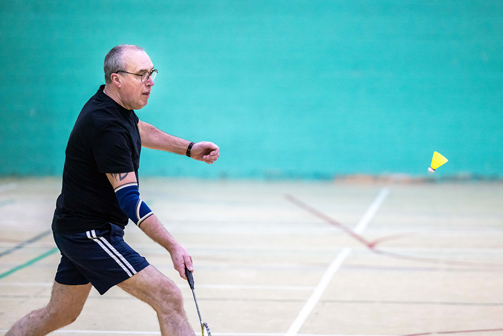 Man holding a badminton racquet in a sports hall