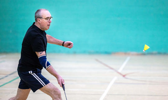 Man holding a badminton racquet in a sports hall
