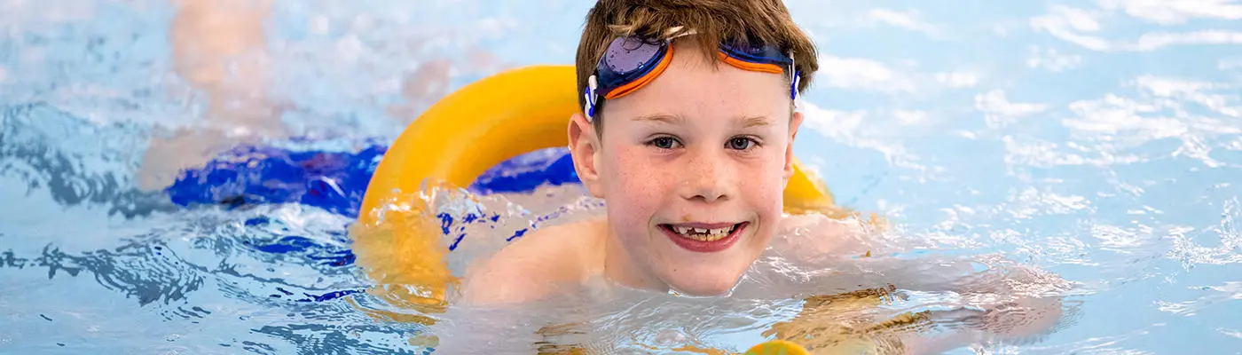 Boy in a pool using a floating aid