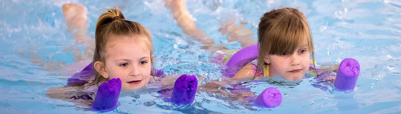 Two children learning to swim in a pool