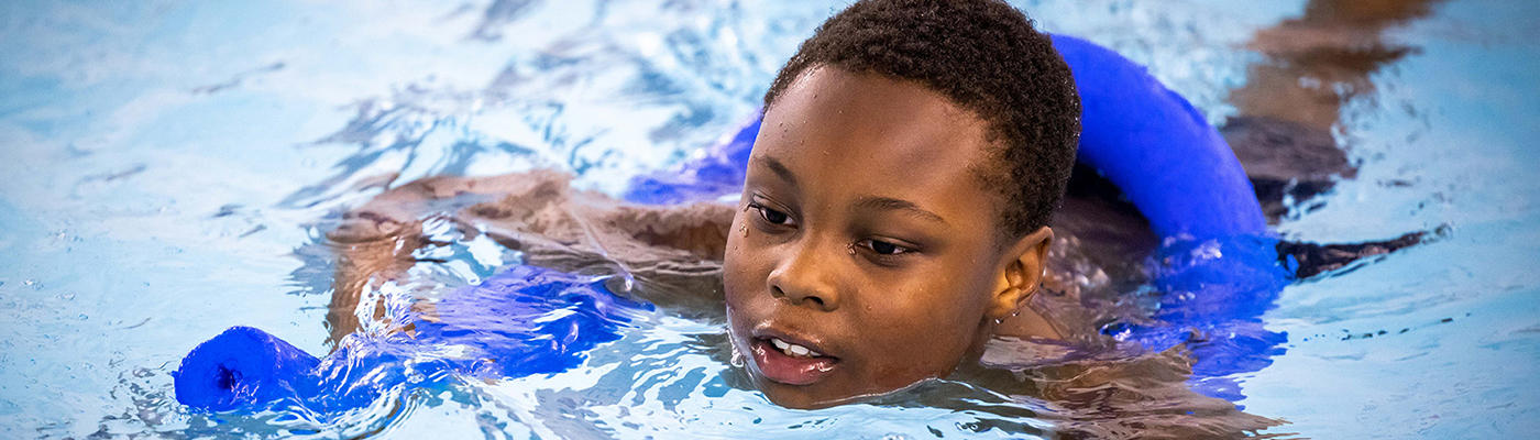 Boy in a pool using a floating aid