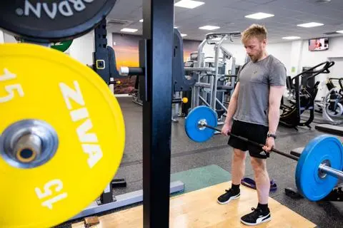 Man in a gym lifting weights on a bar