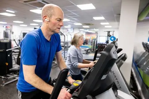 A man and a women on running machines in a gym
