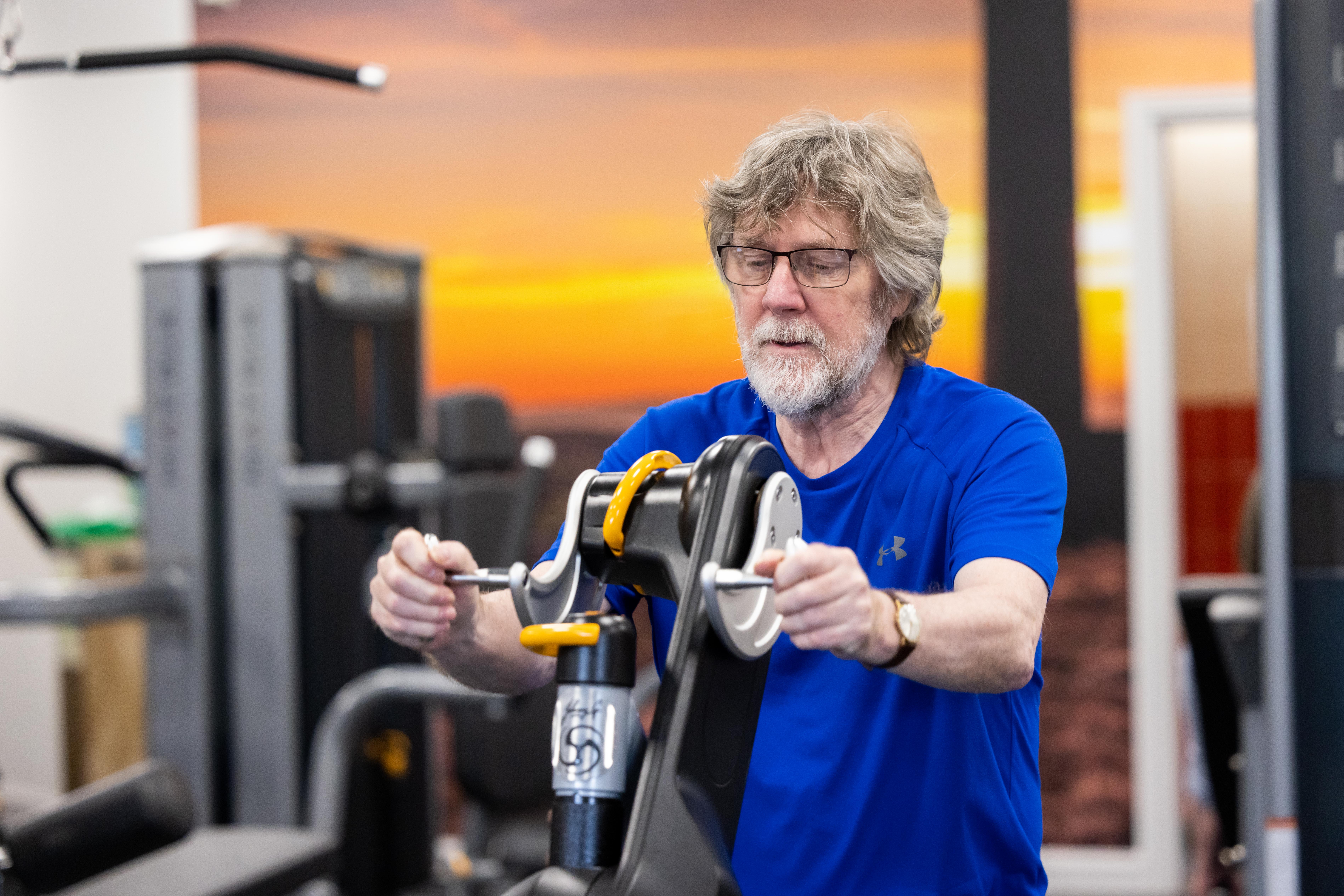Man sat on a handbike in a gym
