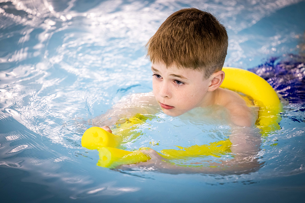 Boy swimming with buoyancy aid