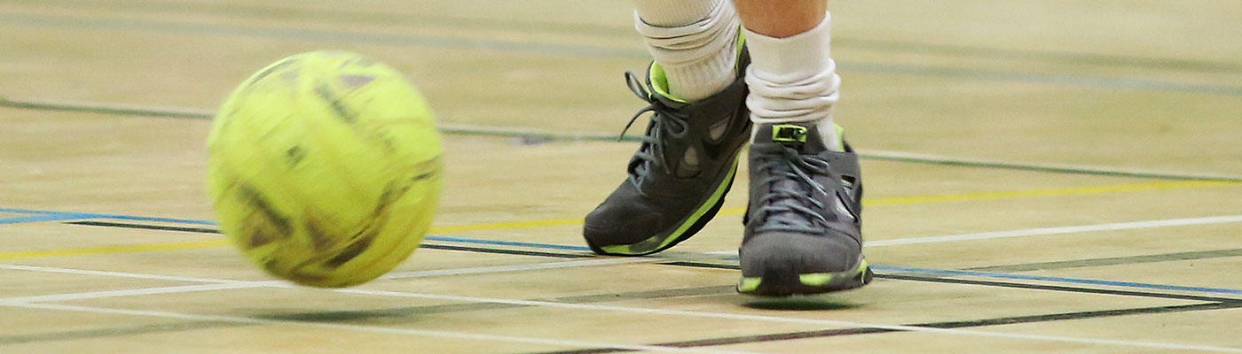 Close up of a person's feet and a football in Castle Leisure Centre sports hall