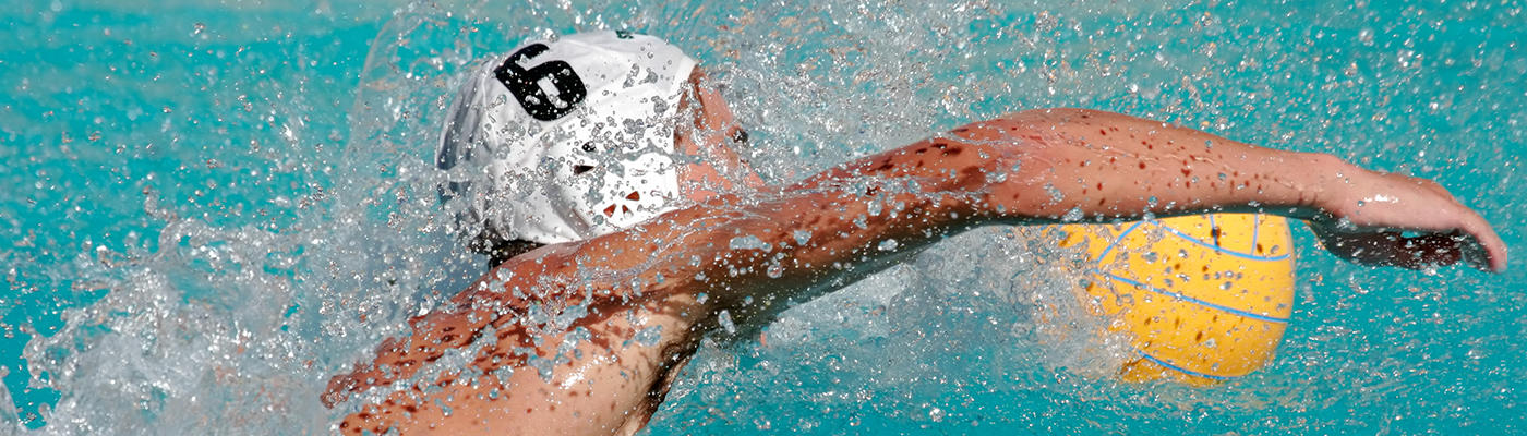 Young man in a swimming pool with a yellow water polo ball